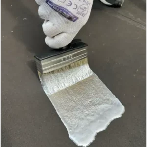 Expert applique une couche de CoolRoof Silver Reflect au pinceau sur un toit plat pour une réflexion solaire optimale.