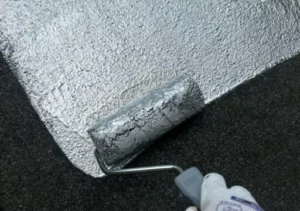 Couvreur applique le revêtement CoolRoof Reflect sur un toit plat avec un rouleau pour une réflexion solaire optimale.
